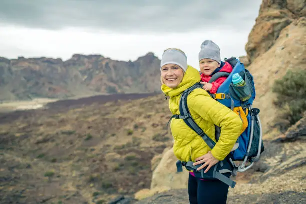 Photo of Happy mother with little boy travelling in backpack