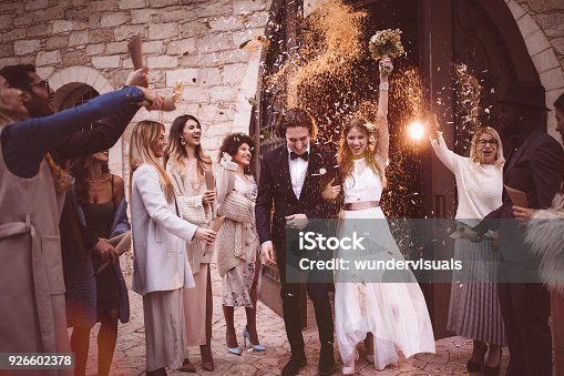 istock Newlywed couple walking out church and celebrating wedding with confetti 926602378
