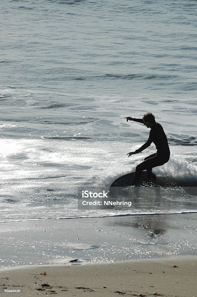 skimboarding silhouette, Santa Cruz, California Skimboarding Santa Cruz style requires a wet suit in the cold water. Skim boarder silhouetted against Pacific Ocean, Santa Cruz, California. Adult Stock Photo