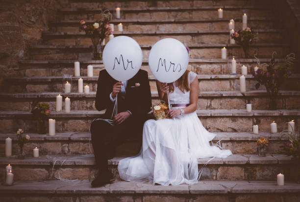 pareja de recién casados sentados en escalones y sosteniendo globos - recién casados fotos fotografías e imágenes de stock