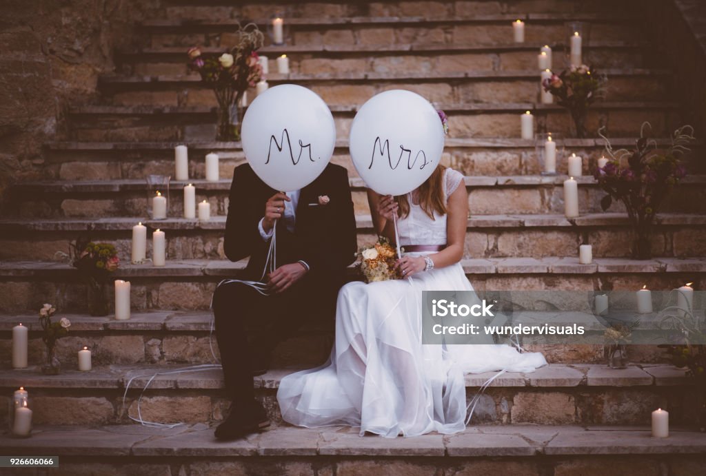 Couple de jeunes mariés assis sur les marches et la tenue des ballons - Photo de Mariage libre de droits