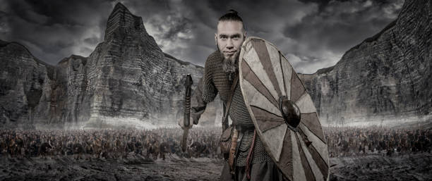 istock Weapon wielding viking warrior alone in front of viking hoard and mountain range 926610406
