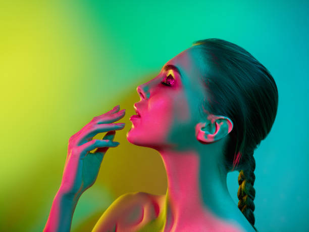 High Fashion model woman in colorful bright lights posing in studio High Fashion model woman in colorful bright lights posing in studio, portrait of beautiful sexy girl with trendy make-up and manicure. Art design, colorful make up. Over colourful vivid background. human face light stock pictures, royalty-free photos & images