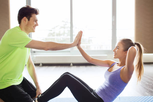 istock woman with personal trainer doing sit ups in gym 926618204