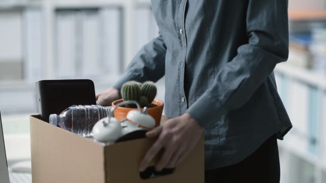 Sad employee packing her belongings and leaving the office after being fired, employment and crisis concept