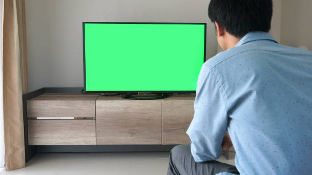 istock Man looking at Television With Green Screen 926626052