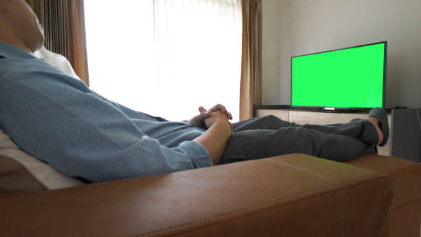 istock Man looking at Television With Green Screen 926626100