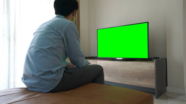 istock Man looking at Television With Green Screen 926626106