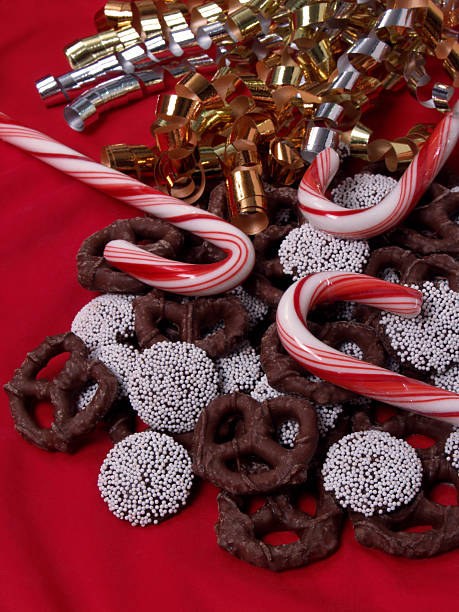 Balas em forma de bengala, Chocolate e Pretzels Nonpareils sobre vermelho - foto de acervo