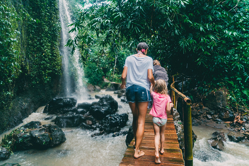 Caucasian mother walking with   daughter  on bridge   near waterfall in Bali, Indonesia