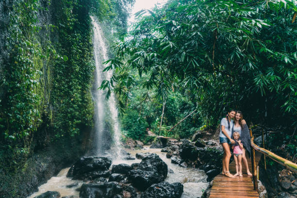 istock Mother with two daughters standing   near waterfall in Bali, Indonesia 926636238