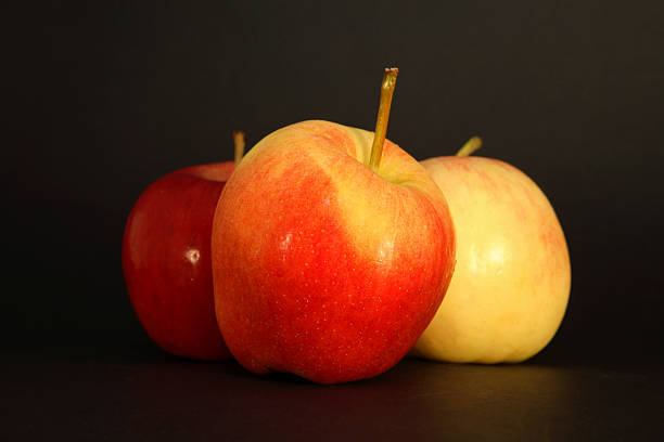 drei äpfel, auf schwarzem hintergrund - three objects three people three animals apple stock-fotos und bilder