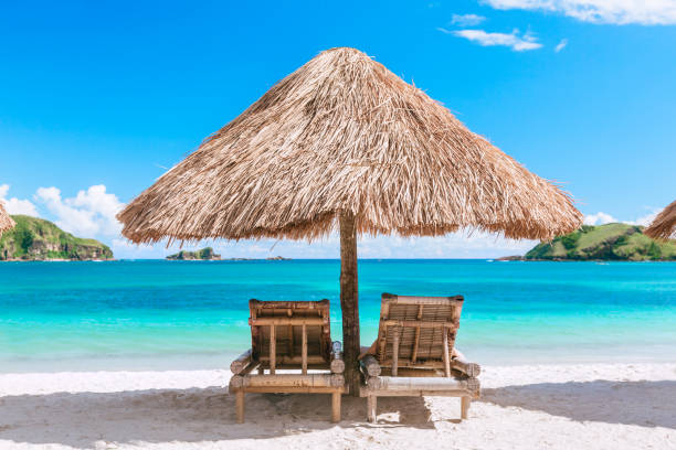istock Straw beach umbrella and wooden chairs on the beach 926648316