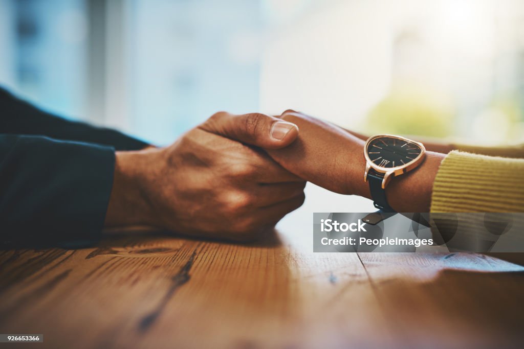 You're in a safe space space now Cropped shot of a man and woman compassionately holding hands at a table Holding Hands Stock Photo