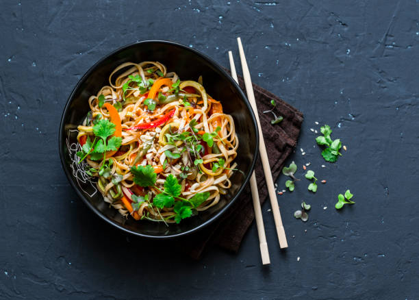 Pad Thai vegetarian vegetables udon noodles in a dark background, top view. Vegetarian food in asian style. Copy space Pad Thai vegetarian vegetables udon noodles in a dark background, top view. Vegetarian food in asian style. Copy space soy sauce photos stock pictures, royalty-free photos & images