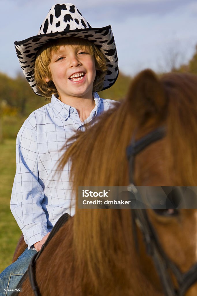 Cowboy In Training A young boy having fun riding a pony and dressed as a cowboy Animal Stock Photo