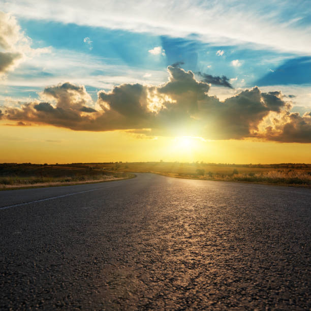 istock Dramatic clouds and low sun in sunset over asphalt road. 926692766