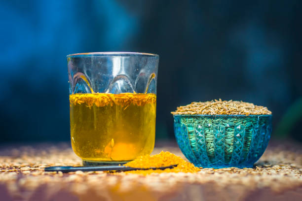 Cumin,Cuminum cyminum with its powder and its extracted water on brown wooden surface. stock photo