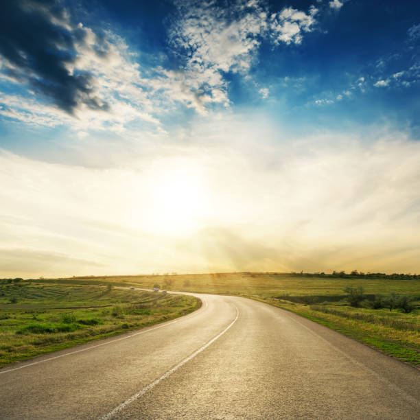 istock road to horizon in sunset. Low clouds with sun over asphalt way 926693090