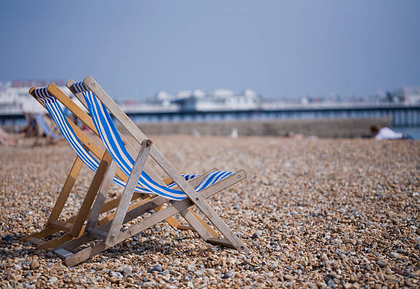 Two blue and white deckchairs on Brighton pebble beach, UK stock photo