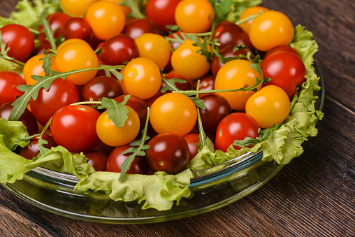 Cherry tomatoes in a glass plate on a wooden background