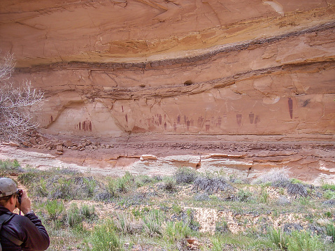 A hiker pauses to photograph the amazing pictographs in the Great Gallery in Horshoe Canyon, a detached unit of Canyonlands National Park, Utah