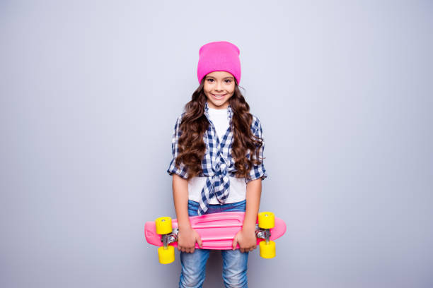 retrato de giro sorridente menina com rosa-placa do patim de chapéu-de-rosa que está pronto para andar a pé a rua sobre fundo cinza - pre adolescent child little girls friendship child - fotografias e filmes do acervo