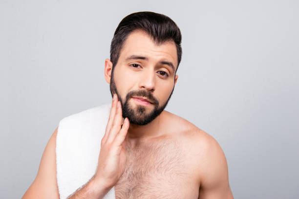 istock Close up portrait of handsome man, enjoying his bristle after bath, having skin problem , making control of his face skin, touching his bristle,  standing over grey background 926708138