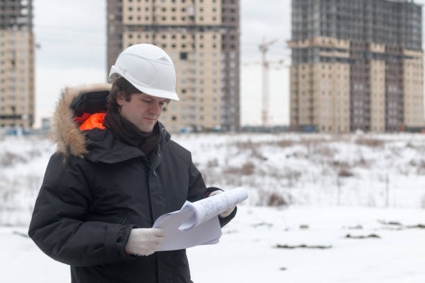 istock Worker or engineer holding drawing in hands and reading it on background of new apartment buildings and construction cranes on background. Architect engineer concept. Soft focus. 926718886