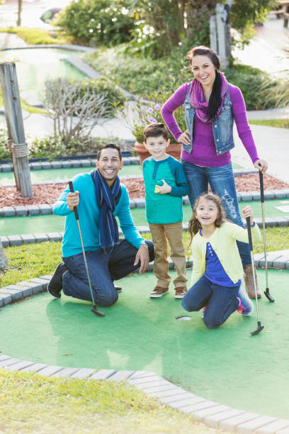 family playing miniature golf - golf four people young adult playing imagens e fotografias de stock