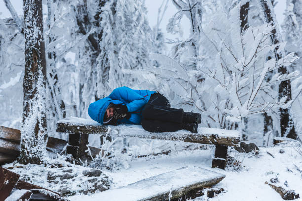 istock Winter man warming up on a bench in a frozen forest 926726510