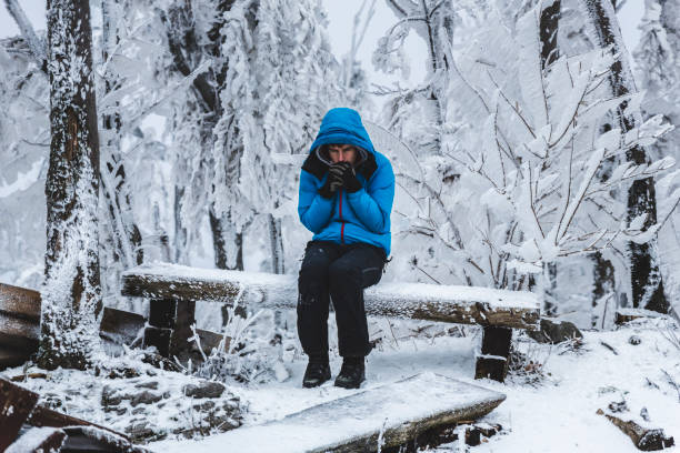 homem sentado num banco, rodeado por uma paisagem de inverno congelado - bench winter snow mountain - fotografias e filmes do acervo