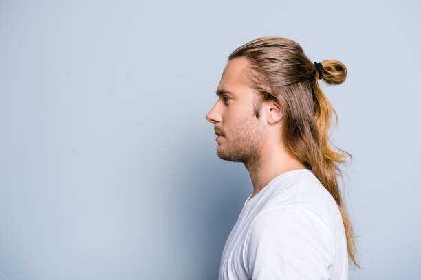 Close up side view photo of serious confident young guy, he has hair bun, isolated on grey background Close up side view photo of serious confident young guy, he has hair bun, isolated on grey background ponytail stock pictures, royalty-free photos & images