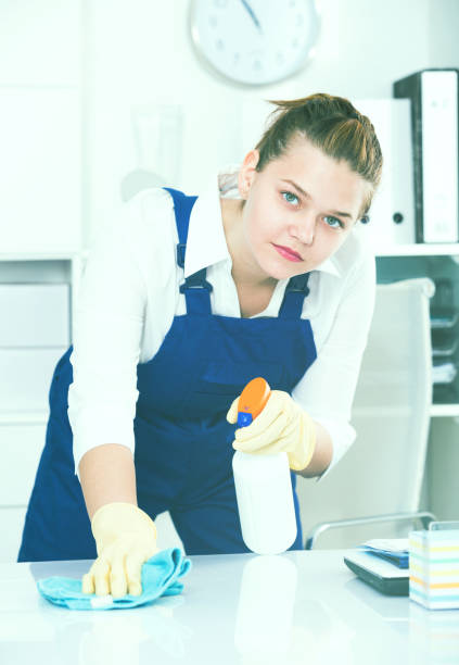 istock Cheerful female cleaner is cleaning dust from the desk 926730156