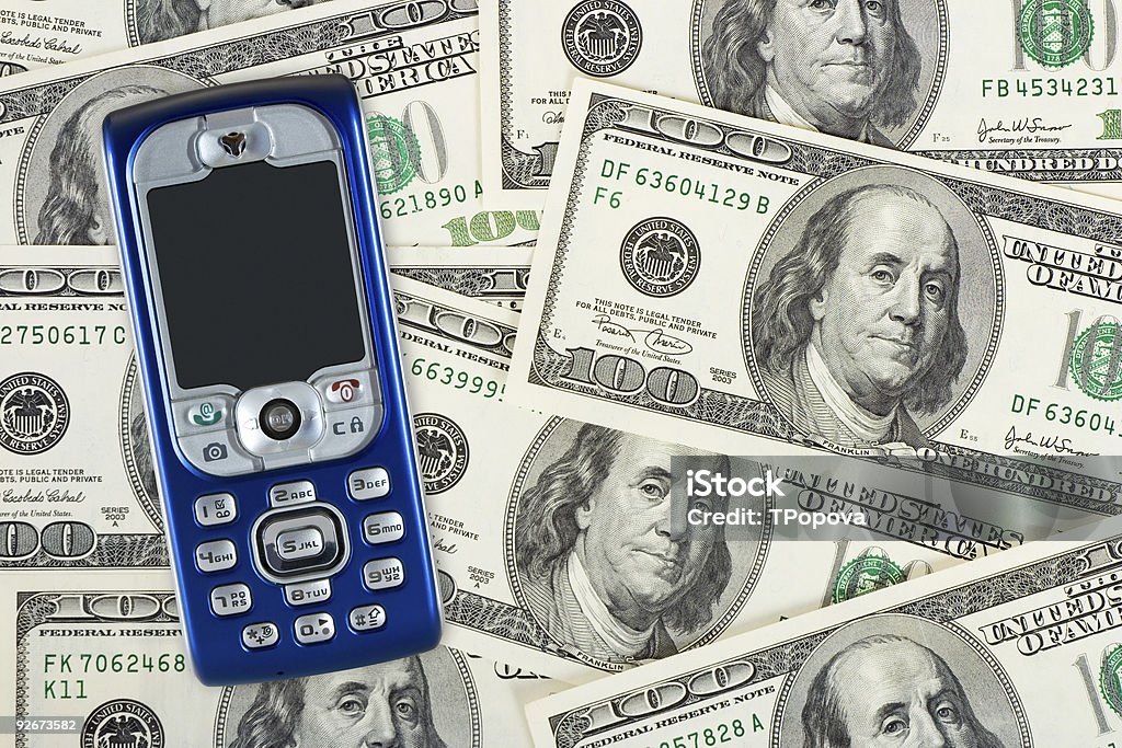 Teléfono móvil sobre fondo de dinero - Foto de stock de Actividades bancarias libre de derechos
