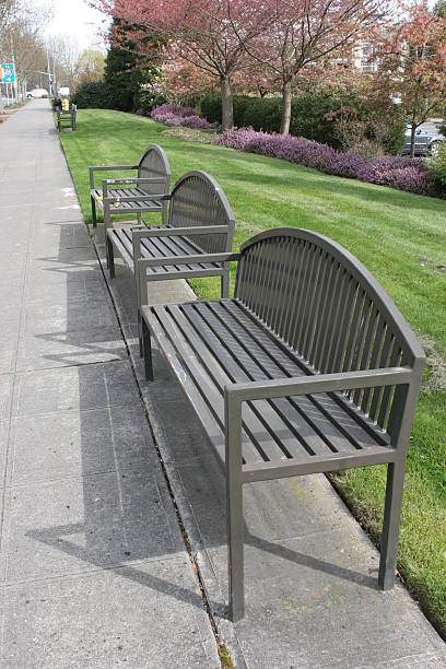 istock Row of bench chairs facing a road 92673834