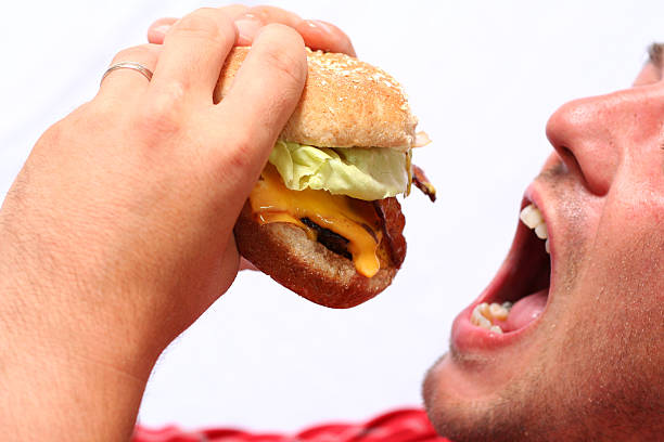 young man eating a juicy hamburger stock photo