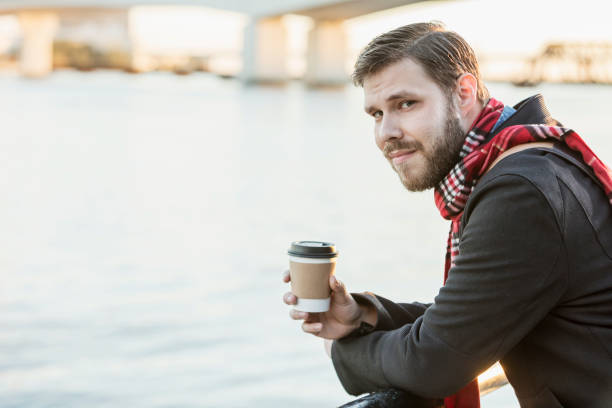 istock Young man in city drinking coffee on waterfront 926741316
