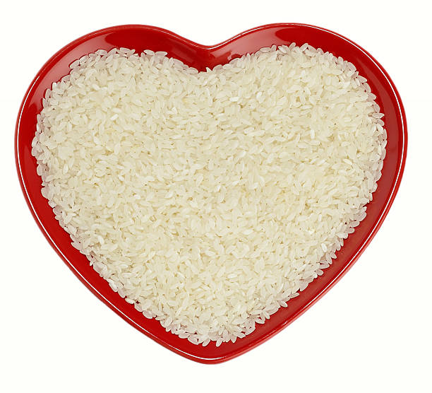 White long-grained rice in heart shape with knife and fork on black background
