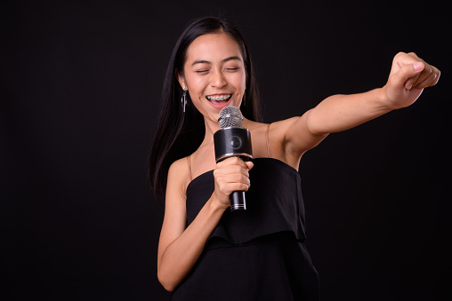 Studio shot of young beautiful Asian woman against black background