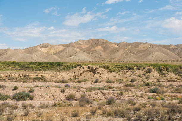View on steppe landscape with barren, sandy hills against blue sky.