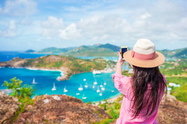 Young tourist woman making photo of English Harbor from Shirley Heights, Antigua, paradise bay at tropical island in the Caribbean Sea View of English Harbor from Shirley Heights, Antigua, paradise bay at tropical island in the Caribbean Sea yacht selfie stock pictures, royalty-free photos & images