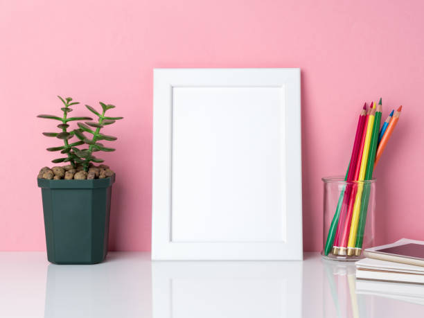 istock Blank white frame, crayon in jar, plant cactus  on a white table against the pink wall with copy space 926796930