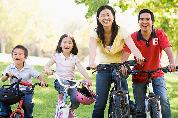 Family on bikes in a park smiling