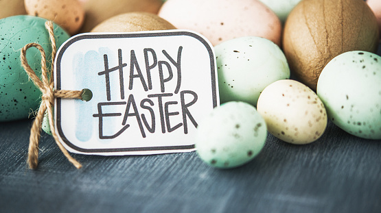 Easter background with pastel speckled eggs on gray and Easter message