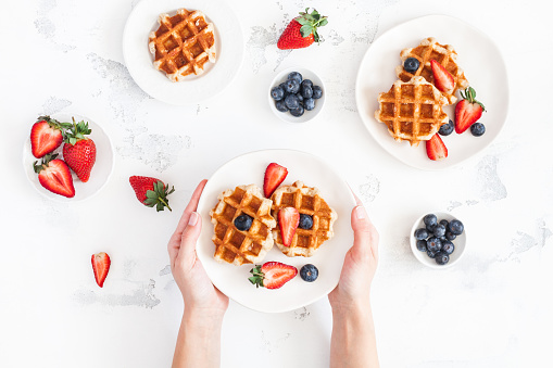 Belgian waffles with fresh strawberry and blueberry on white background. Flat lay, top view