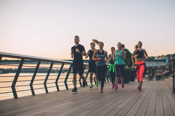 Synchronized group Young men and women running on city streets. They are wearing sport clothing. running stock pictures, royalty-free photos & images