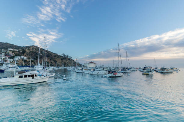 Avalon, California, USA - December 8, 2004: This view of Avalon pier and harbor on Catalina Island shows many smaller boats in the harbor as well as larger Cruise Ship anchored in the area off the Island Harbor and on this beautiful day under a cloudy sky in December the view was great the weather was excellent and another exciting day on Catalina Island is available.