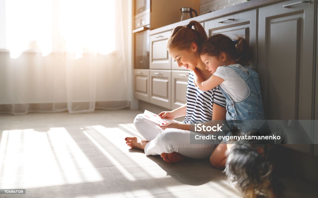 happy mother's day! child daughter congratulates her mother and  read postcard happy mother's day! child daughter congratulates her mother and on  floor in kitchen read postcard Family Stock Photo