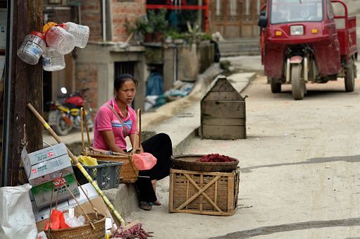 ZHAOXING DONG, CHINA - JUNE 21, 2012: Chinese Miao minority woman selling fresh raspberries fruits in the street.